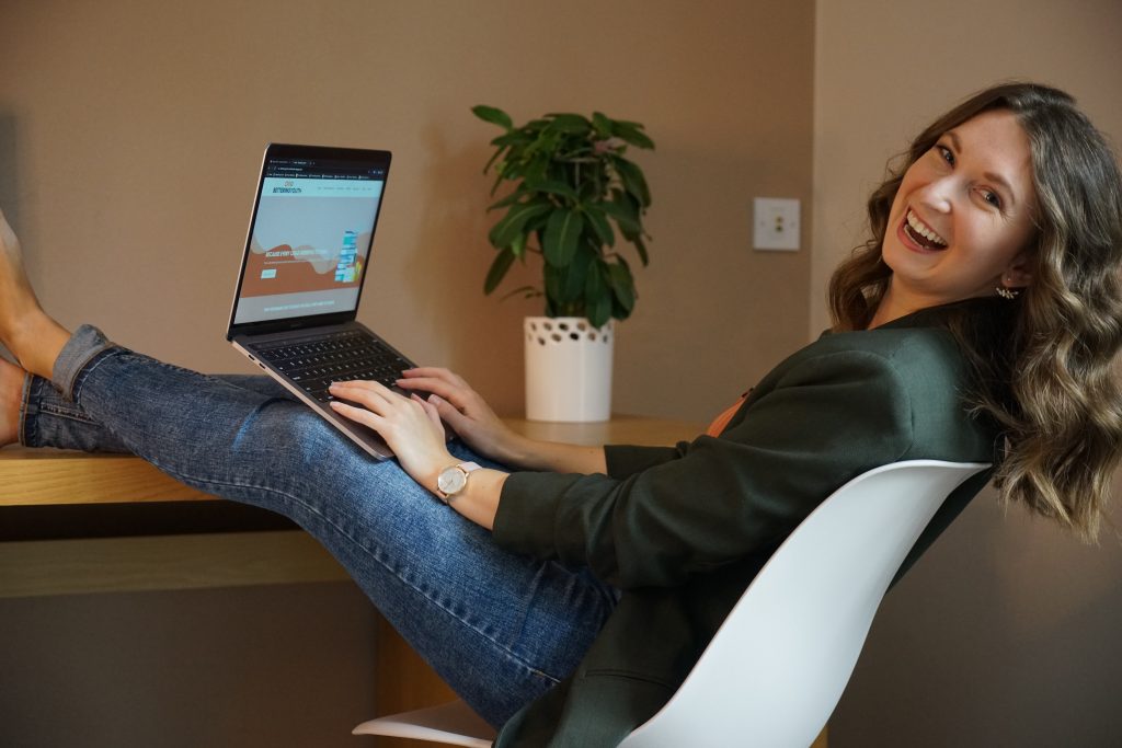 Sarahlynn Hodder sitting at a desk with her laptop open to Bettering Youth website